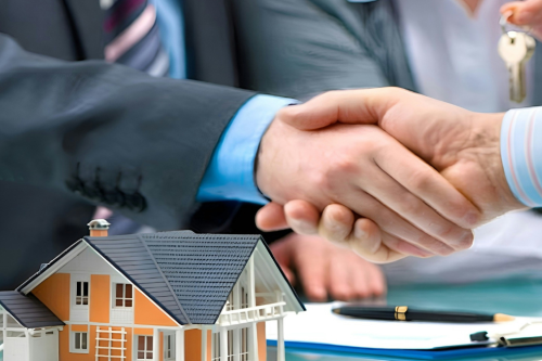 Aperto de mão entre intermediário de crédito e cliente após aprovação de crédito habitação, com chaves e maquete de casa sobre a secretária